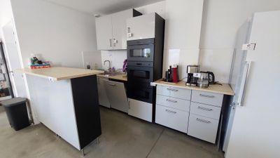 une photo d'une cuisine avec des placards blancs et des appareils électroménagers noirs