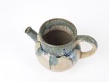 une tasse bleue et blanche avec une anse, posée sur une surface blanche