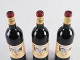 three bottles of red wine sitting next to each other on a white surface