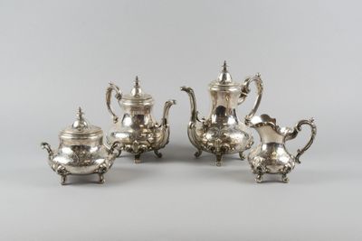 three pieces of silver tea and coffee set on a table