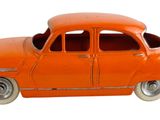 une petite voiture orange posée sur une surface blanche