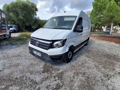 La camionnette blanche est garée sur le gravier, près des arbres.