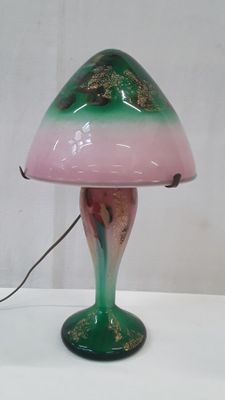 une lampe verte et rose posée sur une table blanche