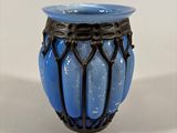 a blue vase with a black rim sitting on a white surface