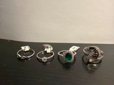 four different rings are sitting on a table with a price tag
