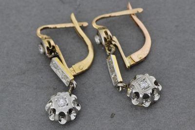 une paire de boucles d'oreilles en or et en argent, ornées de diamants, sur un fond gris