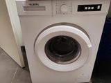une machine à laver blanche posée dans un coin de la cuisine