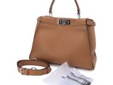 a brown leather handbag with a strap and a small white bag