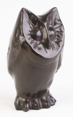 une statue de chouette brune posée sur une surface blanche