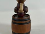 a small wooden figurine of a man sitting on a barrel