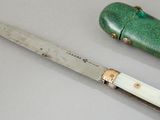 a knife that is laying on a table next to a green case