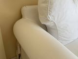 a white couch with a pillow on it in the corner of a room