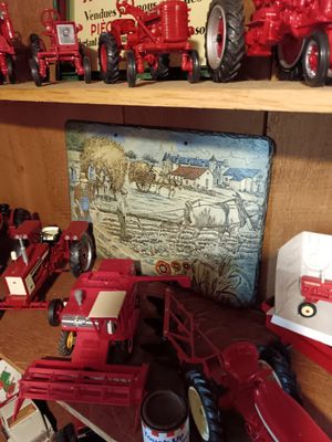 many toy tractors on a shelf in a room