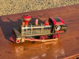 un petit train miniature posé sur une table en bois, avec du gravier en arrière-plan