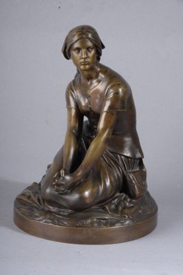 statue en bronze représentant une femme assise par terre, les mains posées sur les genoux