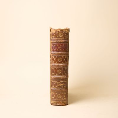 un vieux livre posé sur une table à côté d'un mur blanc