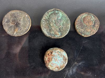 four ancient roman coins sitting on a black surface next to each other