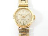 a gold wrist watch with a white dial on it