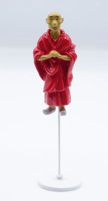 figurine of a monk in red robe on a white stand
