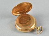 a gold pocket watch sitting on a gray surface