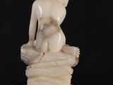 an image of a statue of a woman sitting on top of a rock
