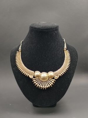 un collier en or sur un présentoir avec un mannequin noir