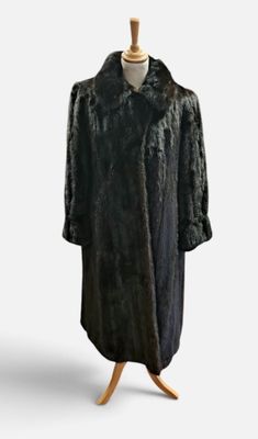 a black fur coat on a mannequin stand against a white background