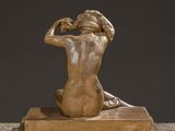 a bronze statue of a woman sitting on top of a wooden block