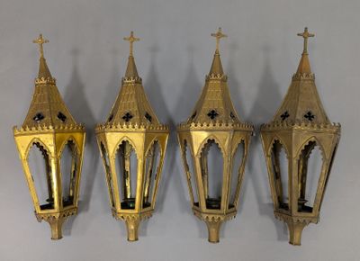 three gold colored lanterns hanging on a wall next to a white wall