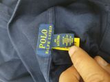 a close up of a person ' s hand holding a polo shirt