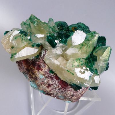 un groupe de cristaux verts et jaunes posés sur un socle transparent