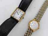 a close up of two watches on a white surface with a black strap