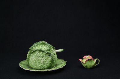 une figurine représentant un chou posé sur une assiette à côté d'une théière
