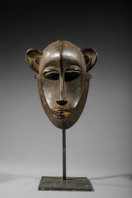 un masque en bois sur un support avec un fond noir