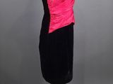 a black and pink dress on a wooden mannequin stand