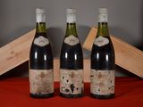 trois bouteilles de vin posées sur une table à côté d'une caisse en bois
