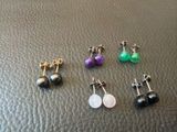 quatre paires de boucles d'oreilles posées sur un support en cuir noir