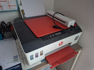 une imprimante posée sur un bureau, recouverte d'un cache rouge