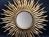 a gold sun shaped mirror sitting on top of a blue wall