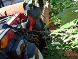 un homme debout à côté d'une moto garée dans l'herbe