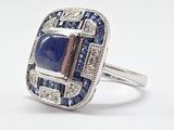 un gros plan d'une bague ornée d'une pierre bleue entourée de saphirs bleus