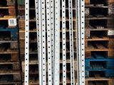 une pile de palettes en bois dans un entrepôt, à côté d'un rayonnage à palettes