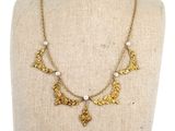 a gold necklace with leaves and pearls on a mannequin mannequin
