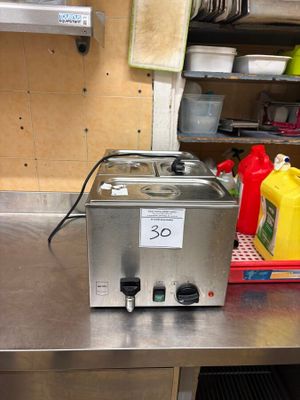 un plan de travail en acier inoxydable dans une cuisine professionnelle, sur lequel sont disposés de nombreux ustensiles de cuisine