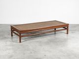 une table basse en bois avec un plateau en verre, posée sur un sol en béton