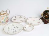 a table with a tea pot, tea pot, plates, and a clock