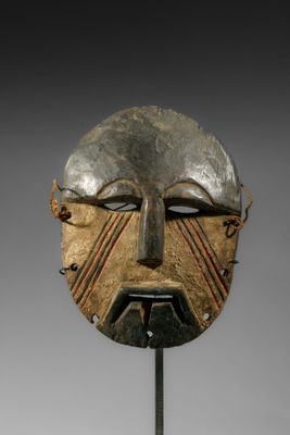 gros plan d'un masque en bois sur un support métallique