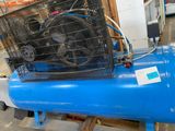 a blue air compressor sitting on a pallet in a warehouse