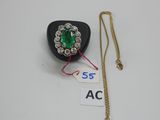 un gros plan sur un collier orné d'une pierre verte et d'une chaîne en or