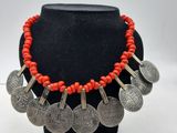 un collier composé de perles de corail rouge et de pièces d'argent